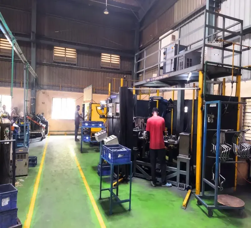 A weld bay with a worker and blue storage bins